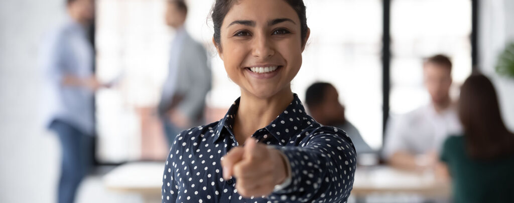 Portrait einer Businessfrau, die mit dem Finger auf den*die Betrachter*in zeigt