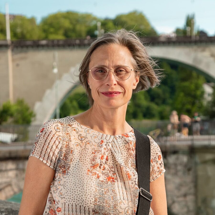 Nahaufnahme einer Frau mit einem freundlichen Ausdruck und floralem Oberteil.