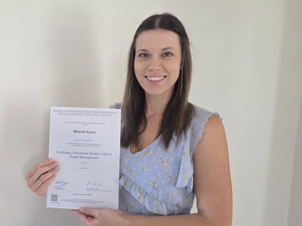 Person hält das Zertifikat ‚Certificate of Advanced Studies (CAS) in Project Management‘ in den Händen.
